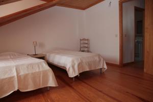 1 dormitorio con 2 camas y suelo de madera en Casa das Tias, en Manteigas