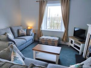 a living room with a couch and a tv at Station Cottage - Gorgeous property with breathtaking views of Neyland Waterway in Neyland