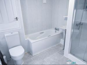 a white bathroom with a toilet and a bath tub at Station Cottage - Gorgeous property with breathtaking views of Neyland Waterway in Neyland +16 photos