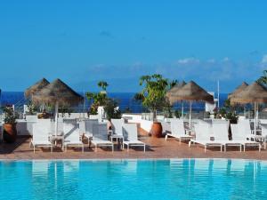 a pool at a resort with white chairs and umbrellas at Flamingo Beach Mate in Adeje