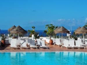 una piscina in un resort con sedie e ombrelloni bianchi di Flamingo Beach Mate ad Adeje
