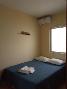 1 dormitorio con cama con sábanas azules y ventana en Pousada Vila Real Flats, en Ouro Preto