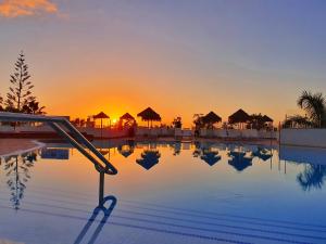 a swimming pool with a slide in front of a sunset at Flamingo Beach Mate in Adeje