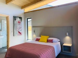 a bedroom with a bed with red and yellow pillows at Palm and Pine Cottage in Cape Town