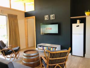 a living room with a white refrigerator and chairs at Palm and Pine Cottage in Cape Town