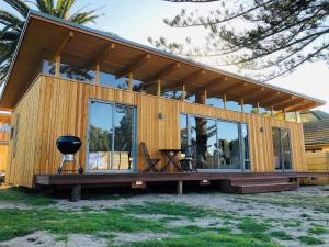 a large wooden house with glass windows and a grill at Palm and Pine Cottage in Cape Town