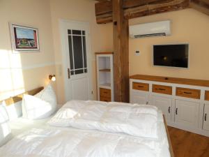 um quarto com uma cama branca e uma televisão de ecrã plano em Speicher Residenz Barth E3 App 9 em Barth