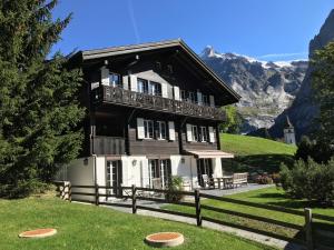 una casa en una colina con montañas en el fondo en Apartment Fortuna 3.5 - Griwarent AG, en Grindelwald