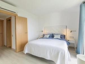 1 dormitorio con 1 cama blanca grande con almohadas azules en Danlux alba, en Tossa de Mar
