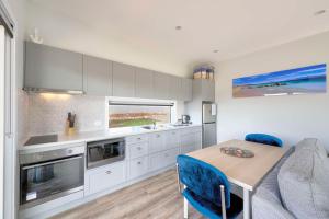 a kitchen with a table and blue chairs at Archella 1 in Coles Bay