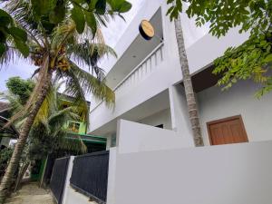 a white house with palm trees in front of it at OYO Life 90152 Garuda Bima Residence Syariah in Tangerang