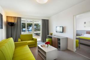 a living room with a yellow couch and a bed at Maistra Select Pineta Hotel in Vrsar