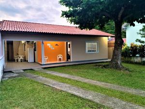 une petite maison avec une porte orange et une cour dans l'établissement Casa Bombinhas, à Bombinhas