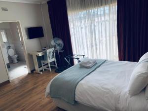 a bedroom with a bed and a desk with a fan at Happy Living Guesthouse in Vereeniging