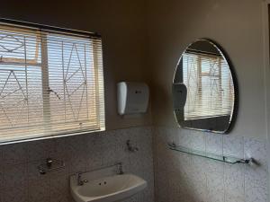 a bathroom with a sink and a mirror at Happy Living Guesthouse in Vereeniging