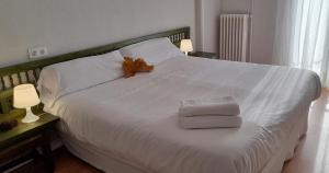 a large white bed with two towels and two lamps at Hotel del Trueno in Ezcaray