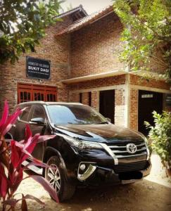 a black suv parked in front of a brick building at Homestay Bukit Dagi Borobudur in Borobudur