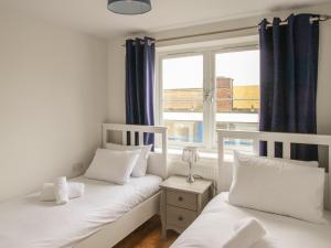 Dos camas individuales en una habitación con ventana. en Nautical Breeze, en Weymouth