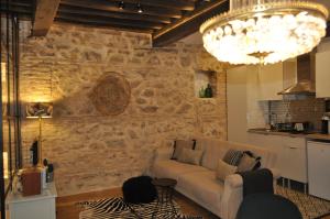 Una sala de estar con un sofá y una pared de piedra. en Lofts amantes de Toledo- LOFT ALCAZAR, en Toledo