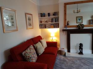 a living room with a red couch and a fireplace at Montrose Guest House in Minehead