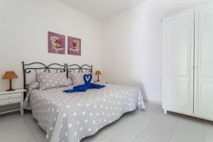 Un dormitorio con una cama con una cinta azul. en El Sombrerito 1, en Caleta de Sebo