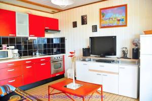 cocina con armarios rojos y TV de pantalla plana en Bungalow - Type F3 - plage de petite anse en Bouillante