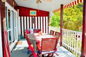 a porch with a table and chairs on a balcony at Charmant bungalow F3 sur la plage de petite anse, Bouillante in Bouillante