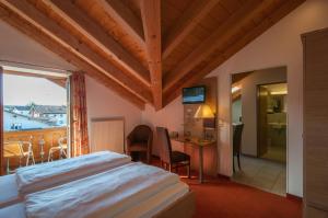 a bedroom with a bed and a desk and a window at Hotel garni Sterff in Seeshaupt