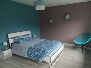 ein blaues Schlafzimmer mit einem Bett und einem blauen Stuhl in der Unterkunft Les Gîtes d' Herquetot " les Bruyères" in Vasteville
