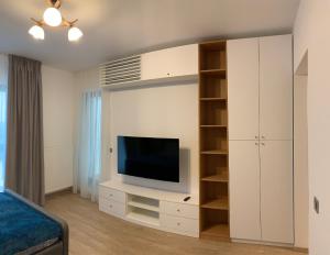 - un salon avec une télévision et une armoire blanche dans l'établissement Comfort Plaza Residence Studio (Lujerului), à Bucarest