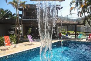 una fuente de agua en una piscina en MarLua Quartos & Suítes en Caraguatatuba