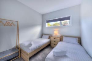 2 łóżka pojedyncze w pokoju z oknem w obiekcie Archella 2 w mieście Coles Bay