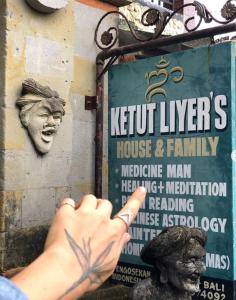 a person pointing at a sign on the side of a building at Liyer Spirit House in Ubud