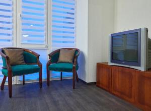 2 Stühle und ein TV in einem Zimmer in der Unterkunft White House in Truskawez