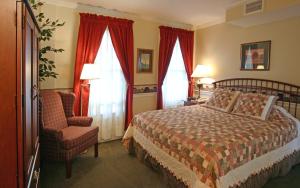 Schlafzimmer mit einem Bett, einem Stuhl und Fenstern in der Unterkunft Bird-in-Hand Village Inn & Suites in Bird in Hand