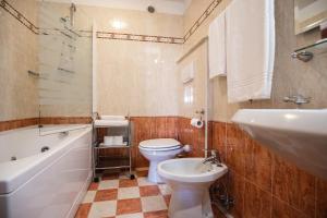 La salle de bains est pourvue d'un lavabo, de toilettes et d'une baignoire. dans l'établissement Hotel Touring, à Predazzo