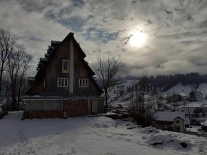 Cabana de pe stanca - hotel في Cîrlibaba Nouă: منزل في الثلج مع الشمس في السماء