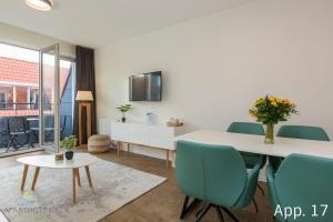 een eetkamer met een witte tafel en groene stoelen bij Luxe 4-persoons appartement in Zoutelande