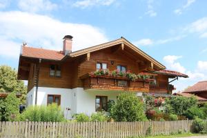 a wooden house with a balcony and a fence at Haus Blumenfeld-Schwaiger in Übersee +9 photos