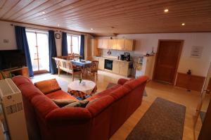 a living room with a red couch and a kitchen at Haus Blumenfeld-Schwaiger in Übersee