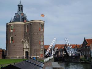 ein großes Backsteingebäude mit einem Uhrturm neben einem Fluss in der Unterkunft Markermeerlogies in Bovenkarspel