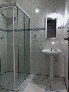 uma casa de banho com um chuveiro, um lavatório e um espelho. em Pousada Manaca em Paraty