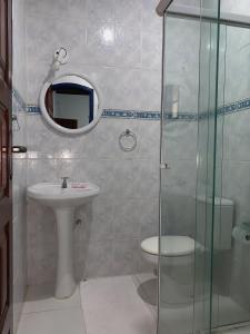 a bathroom with a sink and a toilet and a mirror at Pousada Manaca in Paraty