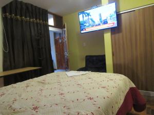 a bedroom with a bed and a flat screen tv at Hotel Sueños Dorados in Juliaca