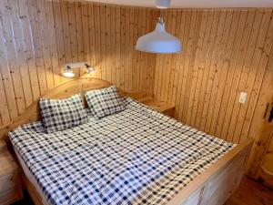 Cama en habitación de madera con lámpara y almohadas en Schmirnhaus, en Schmirn