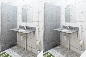 a bathroom with two sinks and two mirrors at Piúma Palace Hotel in Piúma