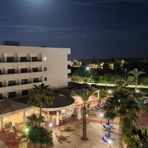 a building with a courtyard with palm trees at night at Nissiana Hotel & Bungalows in Ayia Napa