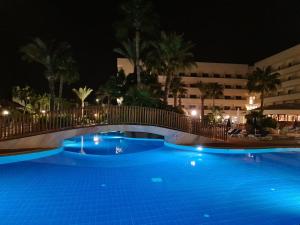 a swimming pool at night with a bridge over it at Nissiana Hotel & Bungalows in Ayia Napa