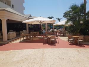 an outdoor patio with tables and chairs and umbrellas at Nissiana Hotel & Bungalows in Ayia Napa