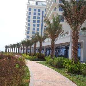 a walkway in front of a building with palm trees at 2 Bedroom Deluxe Beach Apartment Al Marjan in Ras al Khaimah